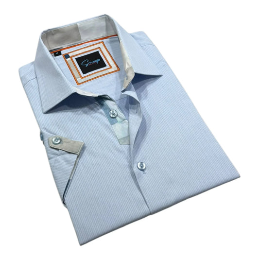 Folded light blue dress shirt with a brand label on a white background