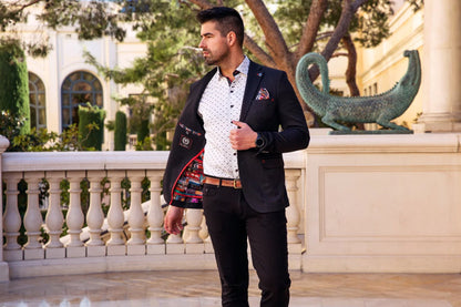 Man in formal attire standing outdoors with decorative elements in the background