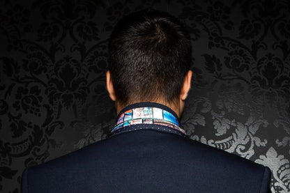 Person wearing a patterned shirt collar against a dark, textured wall.