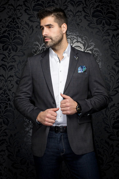 Man wearing a dark blazer over a white shirt with a patterned background