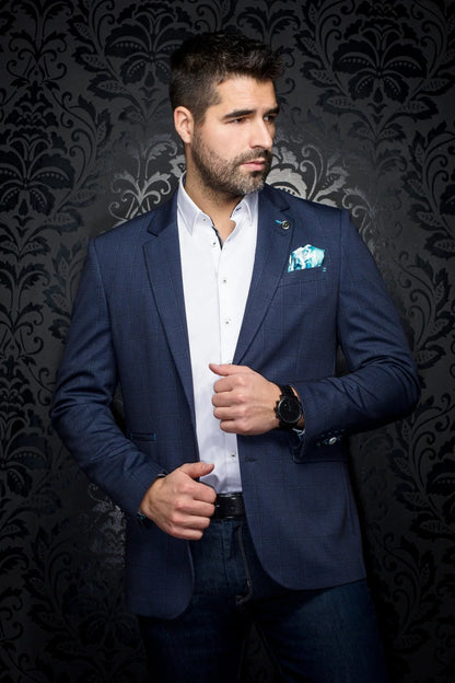 Man wearing a blue blazer over a white shirt with a patterned dark background