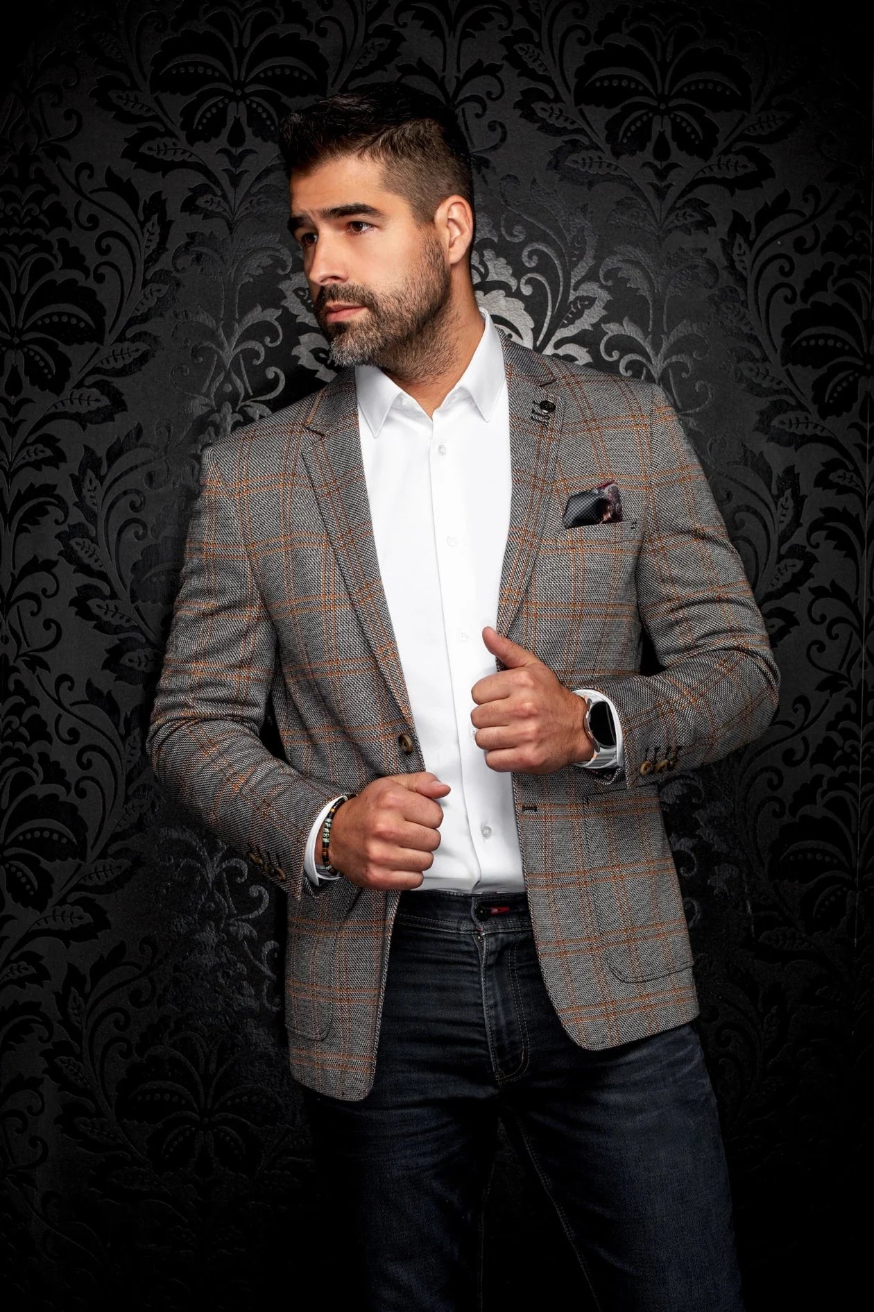 Man wearing a patterned blazer over a white shirt with a dark background