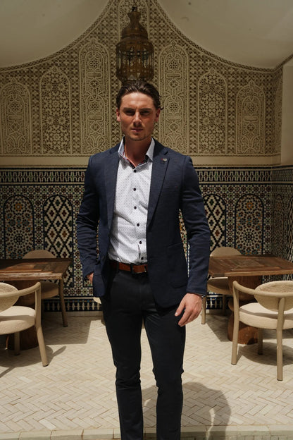 Man in a suit standing in a decorated room with tables and chairs.