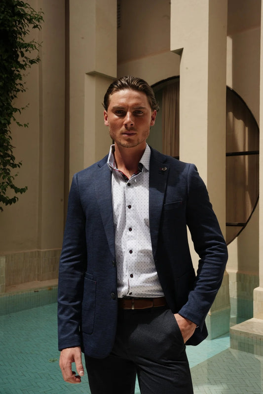 Man in a blue blazer standing in front of architectural columns