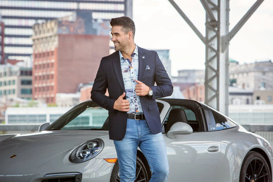Man in a suit standing next to a car with a cityscape background