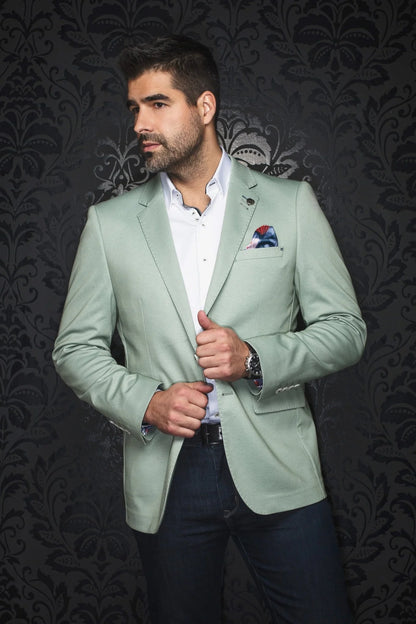 Man wearing a light green blazer over a white shirt with a dark background