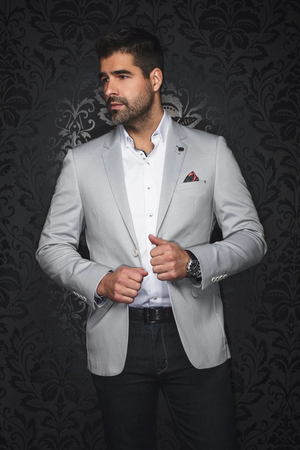 Man wearing a light gray blazer over a white shirt with a dark background