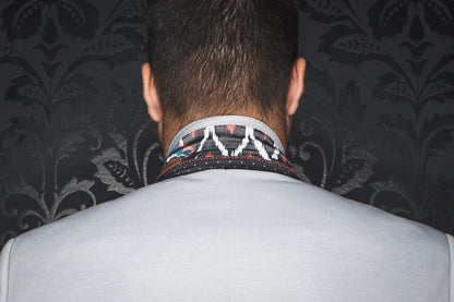 Person wearing a patterned necktie with a dark, decorative wall in the background