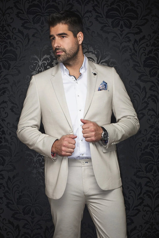 Man wearing a beige suit with a dark patterned background