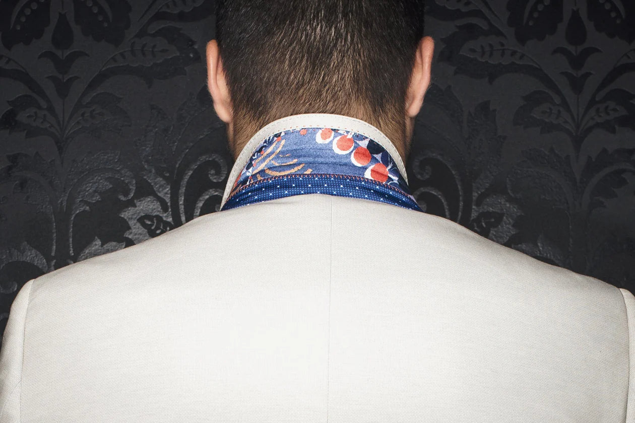 Person wearing a patterned necktie with a dark, decorative wall in the background