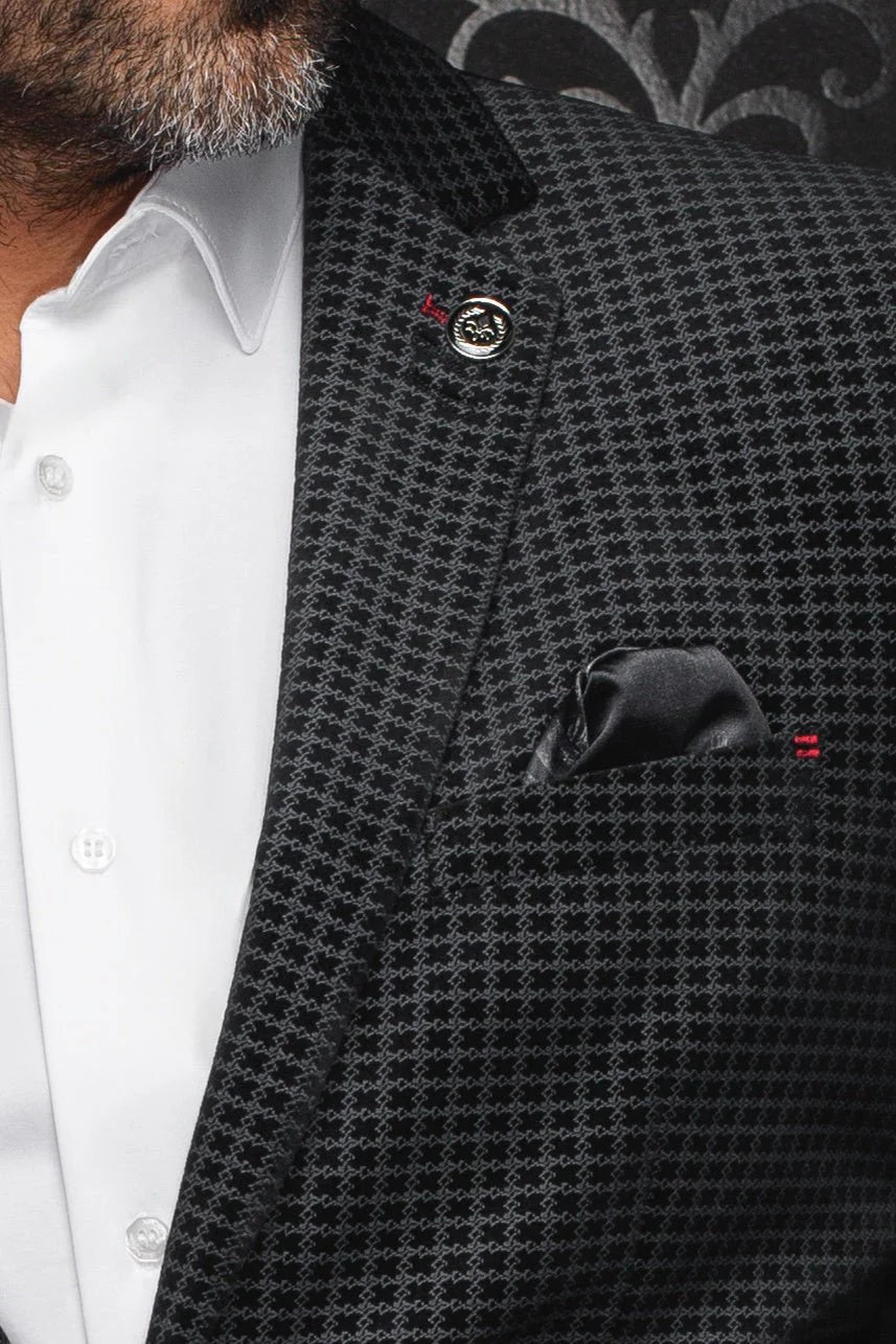 Close-up of a person wearing a black patterned suit jacket over a white shirt.