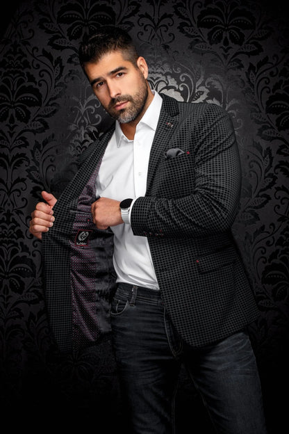 Man wearing a checkered blazer over a white shirt on a dark patterned background