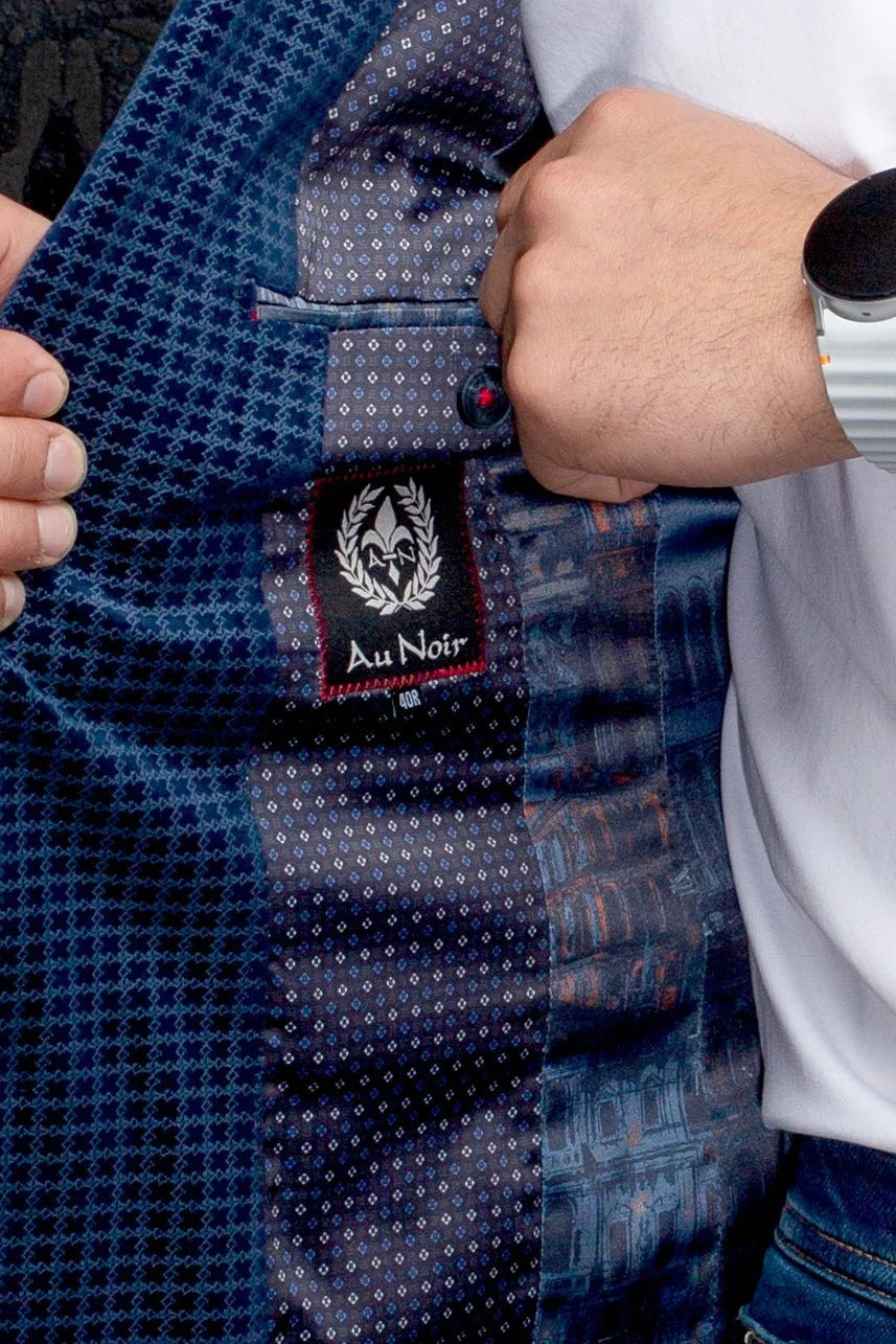 Close-up of a blue patterned shirt with a brand label, held by a person wearing a white shirt.
