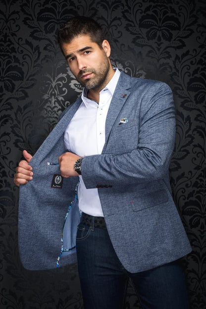 Man wearing a gray blazer over a white shirt with a dark patterned background