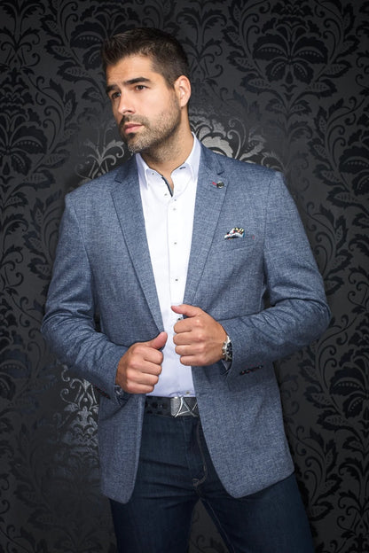Man wearing a blue blazer over a white shirt with a dark patterned background