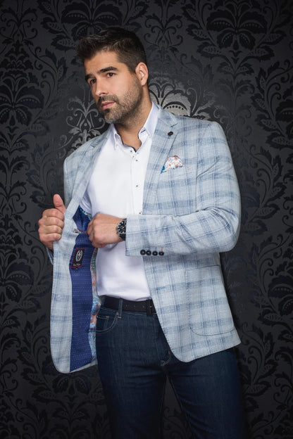Man wearing a light blue checkered blazer over a white shirt with a dark patterned background