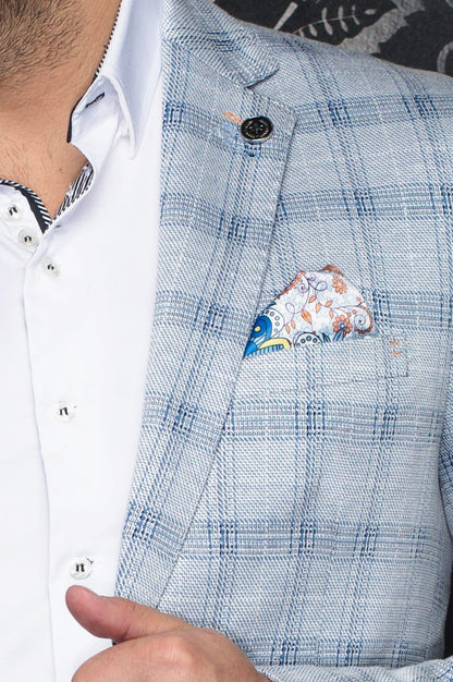 Close-up of a blue checkered jacket with a floral pocket square, worn over a white shirt.