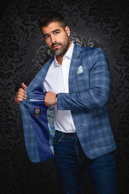 Man holding a blue checkered blazer against a dark patterned background