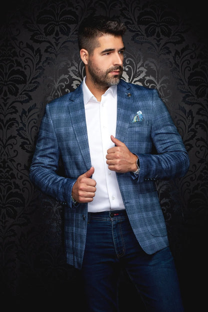 Man wearing a blue checkered blazer over a white shirt with a dark patterned background