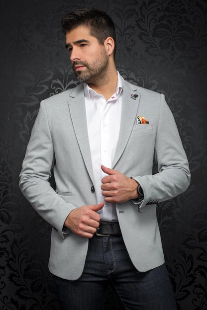 Man wearing a light gray blazer over a white shirt with a dark background