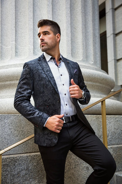 Man in a stylish blazer and pants standing against a stone building background