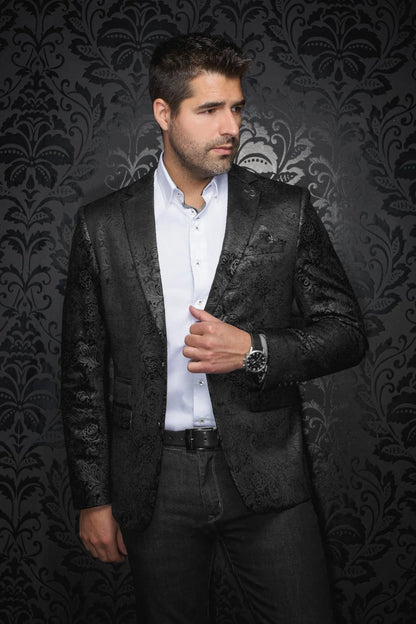 Man wearing a black patterned blazer over a white shirt against a dark, decorative background
